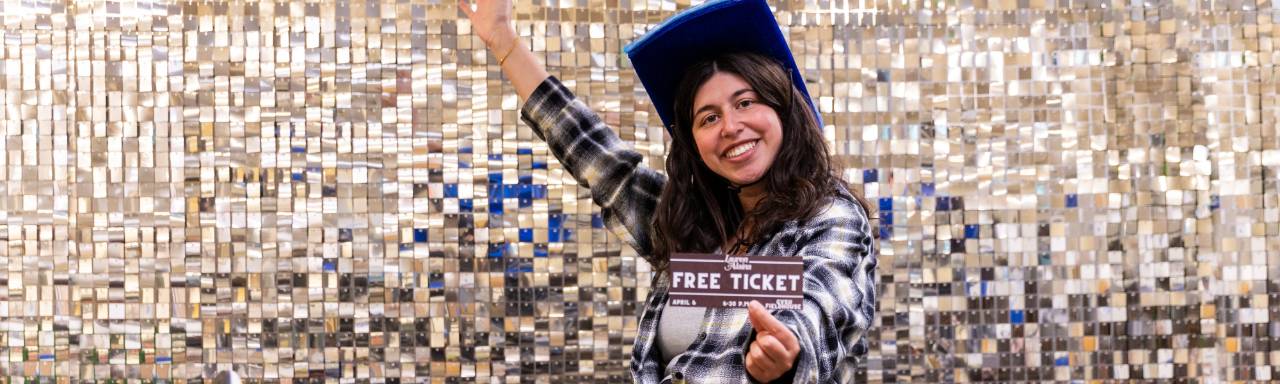 A student posing with a ticket that says Free Ticket for a giveaway for the Spring Concert
